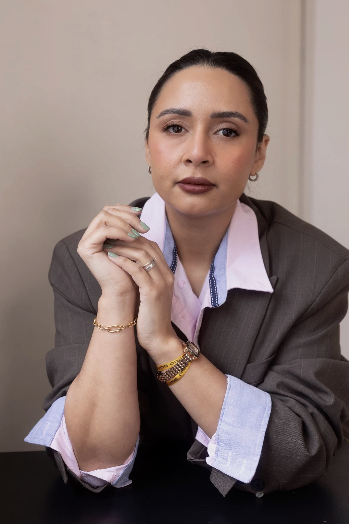 Anaelly Lima looking at the camera, hands folded, in a soft brown blazer.
