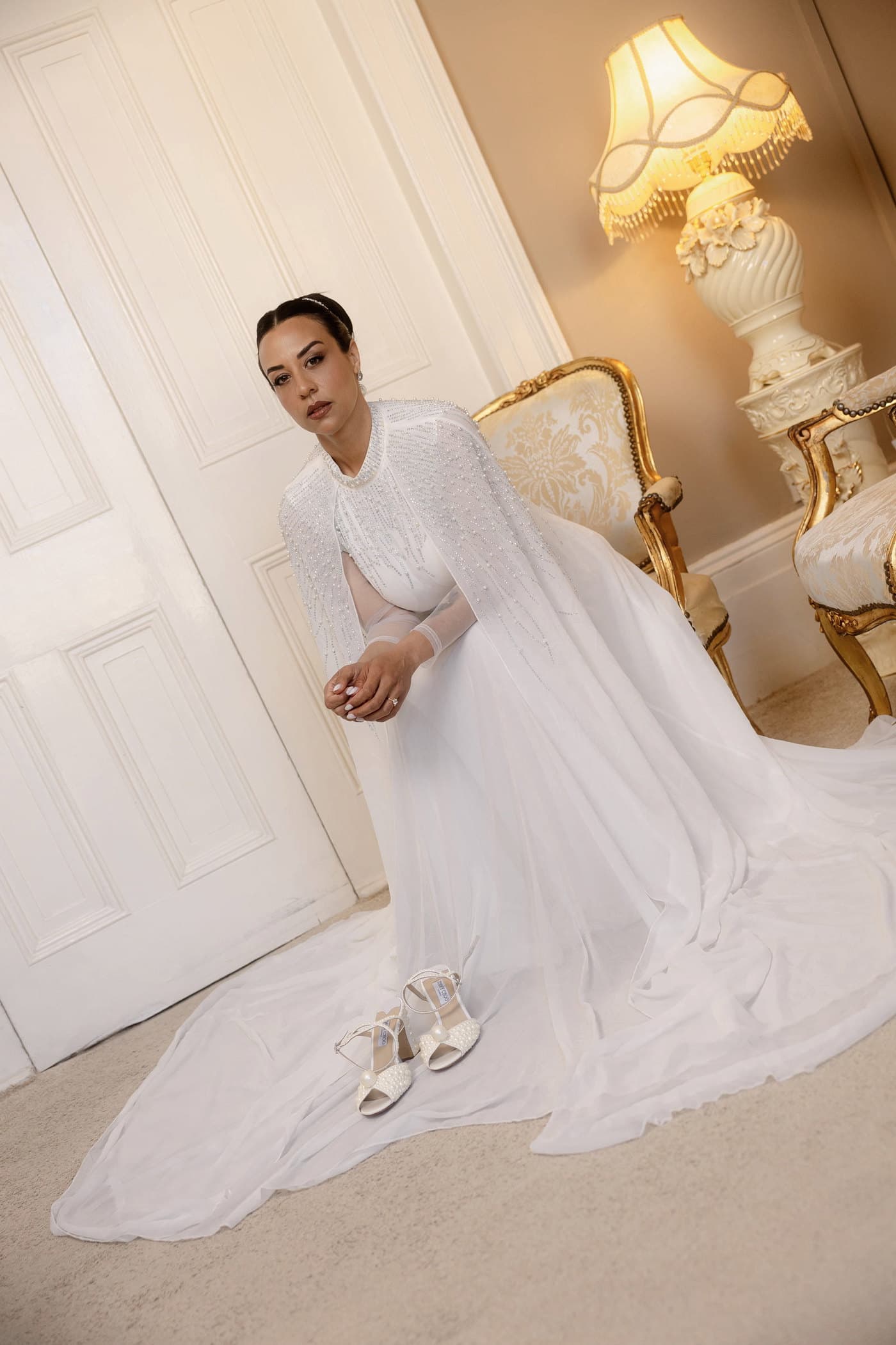 Bride bending to put on her shoe in a warmly lit room.
