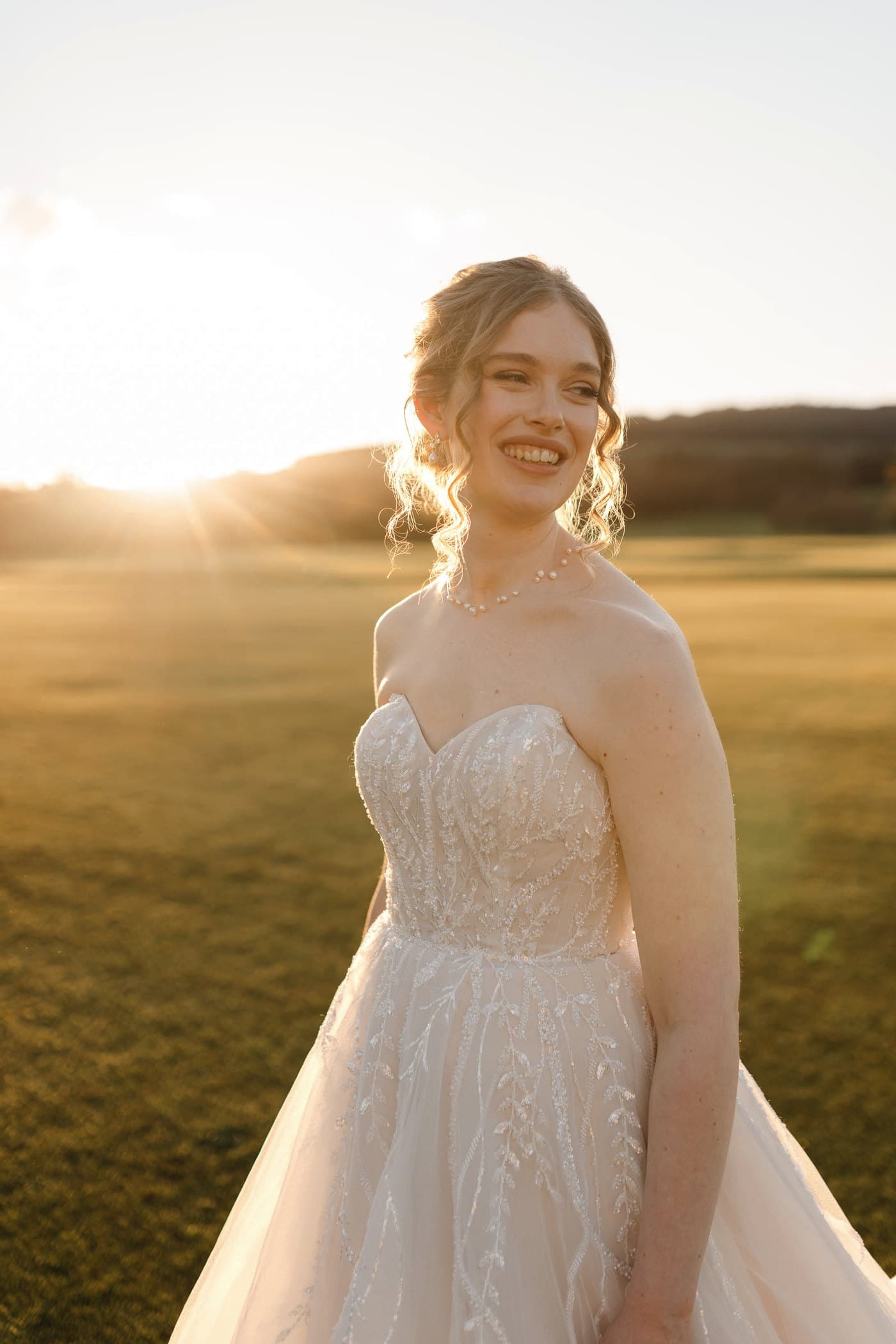 Bride outdoors in late afternoon light, warm gold across her face.